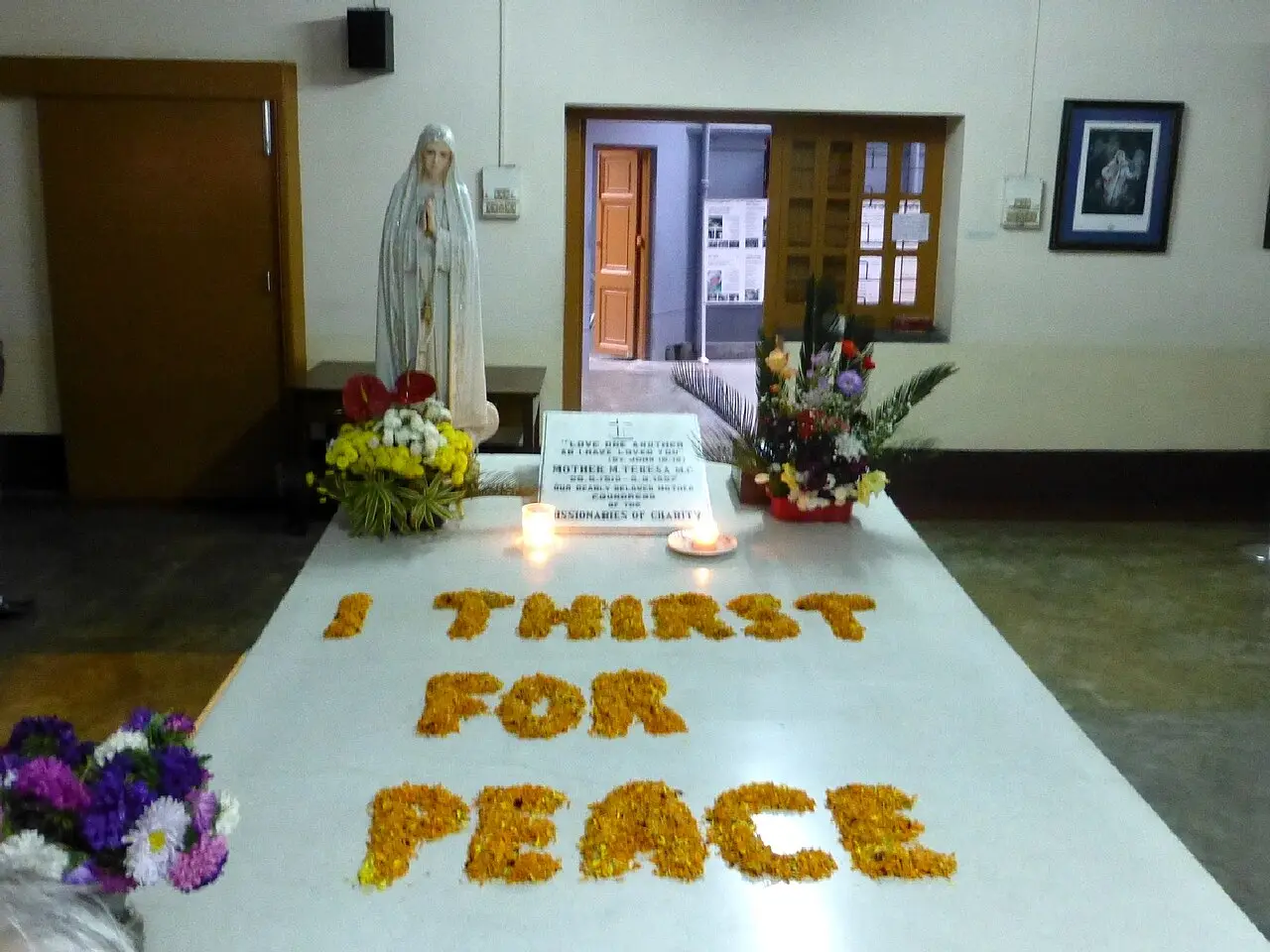 Mother Teresa's tomb at the Mother House of the Missionaries of Charity in Kolkata, decorated with marigold petals spelling 'I thirst for peace'.