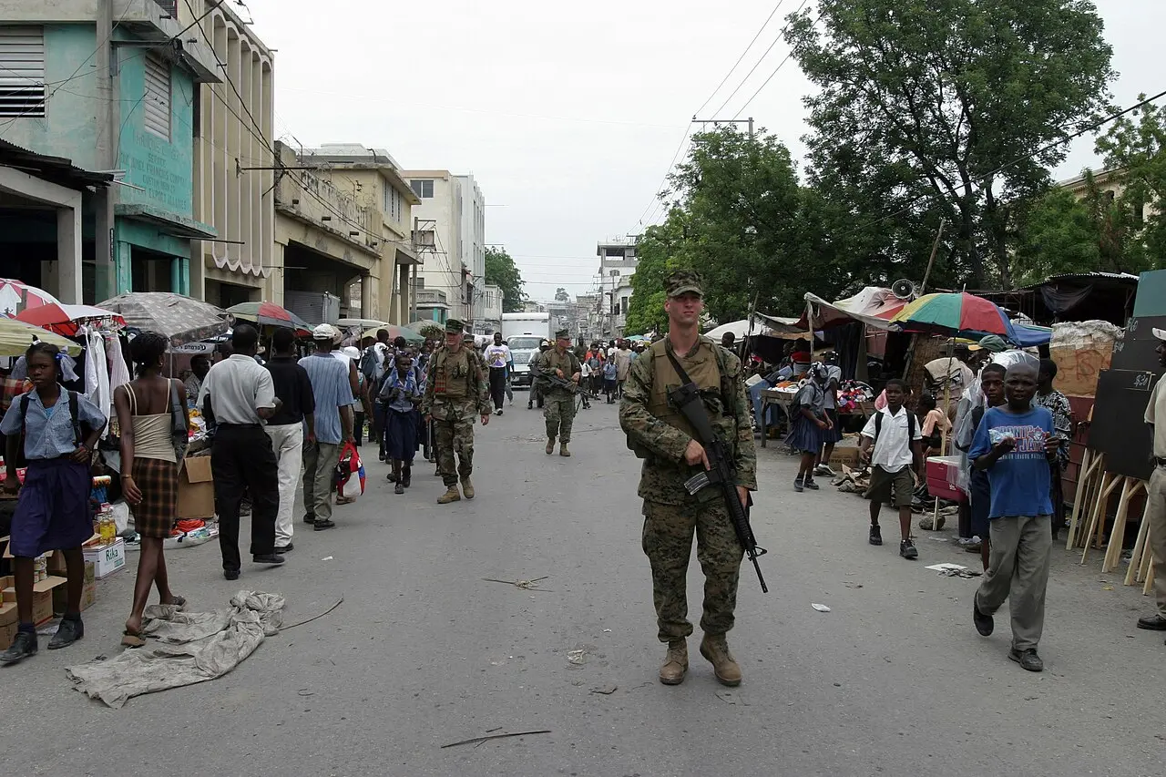 U.S. Marines on patrol walking down a busy market street in Port-au-Prince, Haiti, in 2004, with local residents going about their day