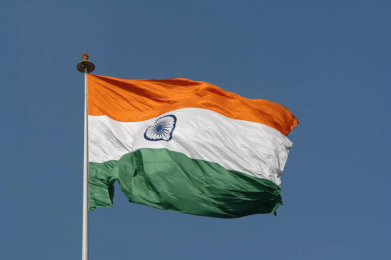 The Indian tricolor flag with the Ashoka Chakra flying against a blue sky.