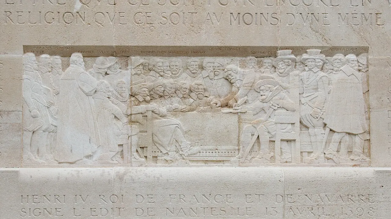 Stone bas-relief on Geneva's Reformation Wall showing Henri IV of France signing the Edict of Nantes in 1598, with a carved inscription below noting the edict was signed on April 13, 1598