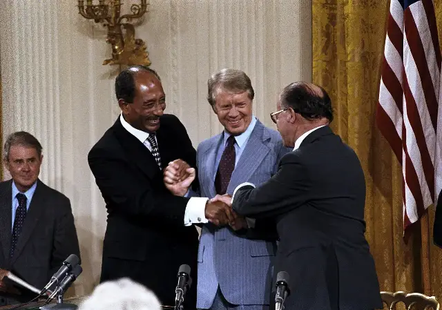 Anwar Sadat, Jimmy Carter, and Menachem Begin join hands after signing the Camp David Accords on September 17, 1978