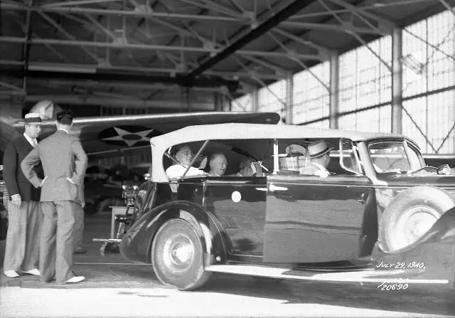 President Franklin D. Roosevelt riding in an open car in an aircraft hangar at Langley Field in July 1940.