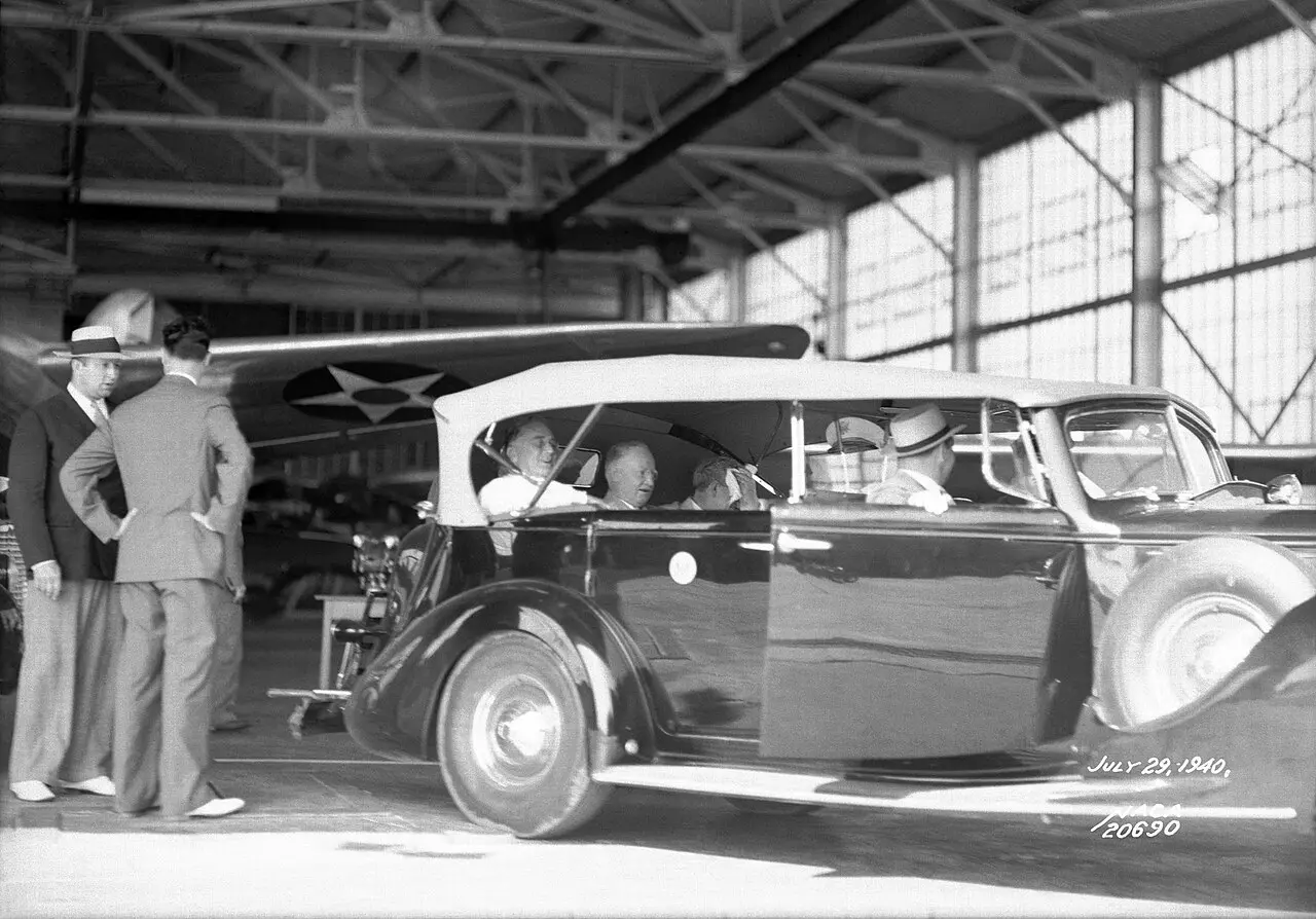 President Franklin D. Roosevelt riding in an open car in an aircraft hangar at Langley Field in July 1940.
