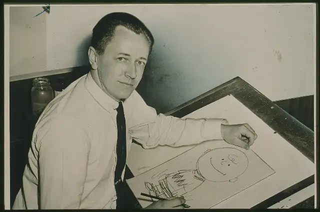Charles Schulz at his drawing table in 1956, drawing Charlie Brown
