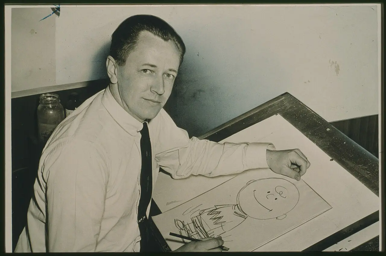 Charles Schulz at his drawing table in 1956, drawing Charlie Brown