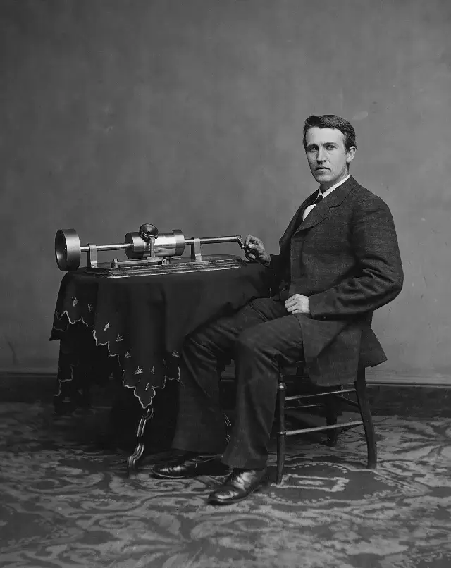 Thomas Edison seated beside his phonograph in a studio portrait taken around 1878.