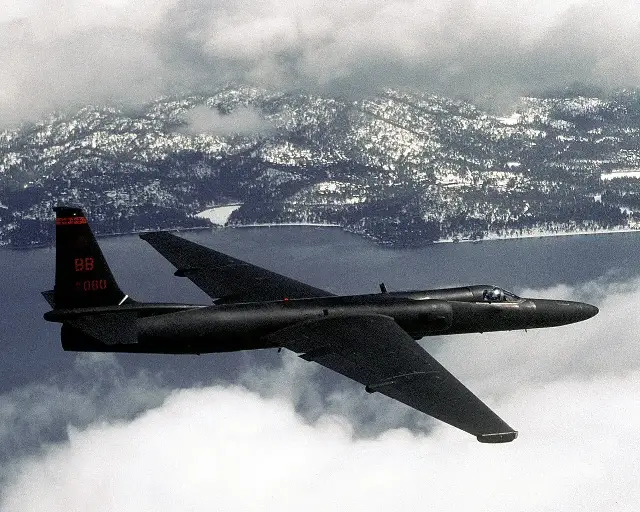 A black U-2 reconnaissance aircraft in flight over mountains