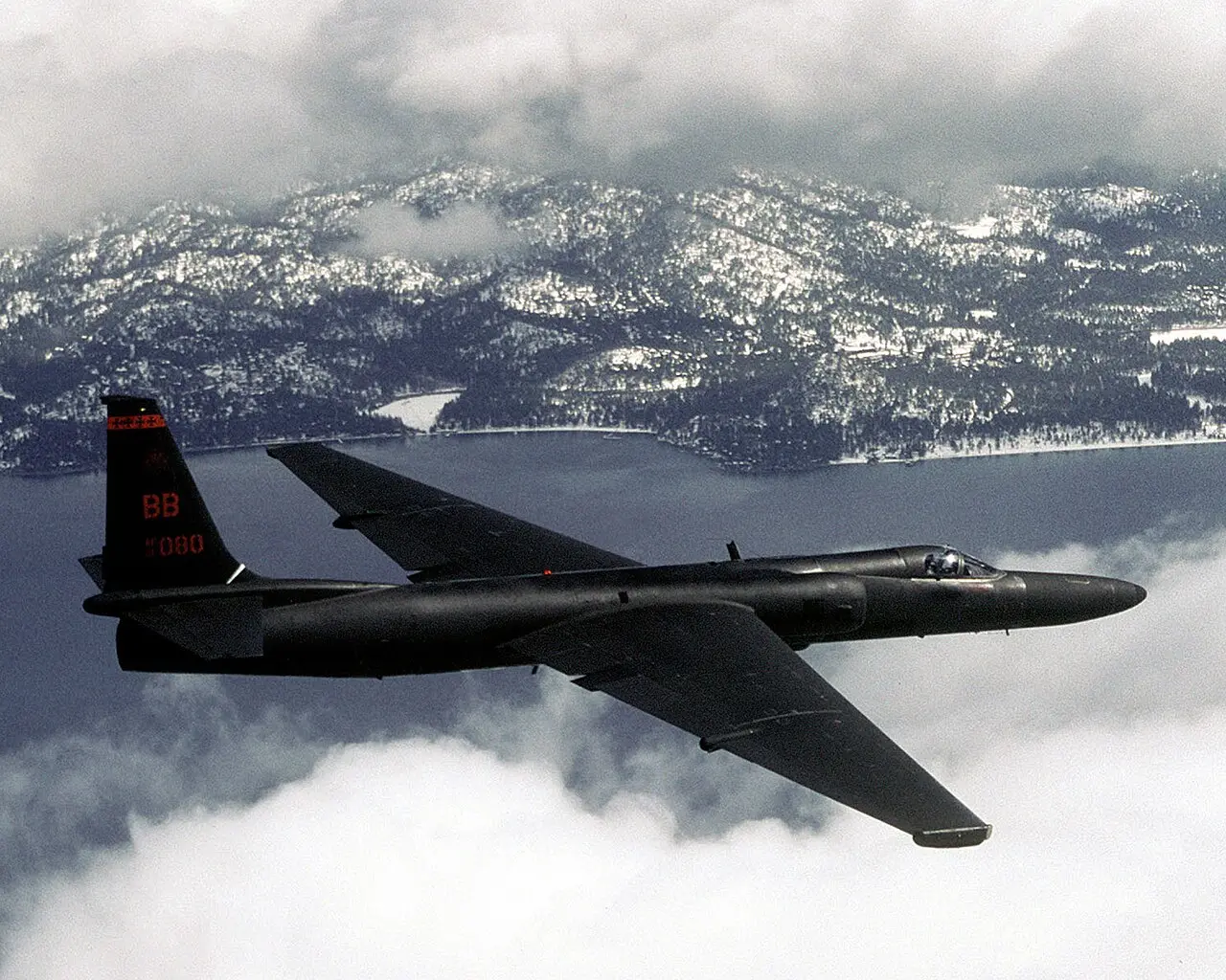A black U-2 reconnaissance aircraft in flight over mountains