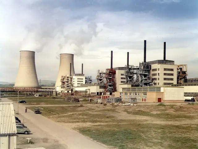 A color photograph of Calder Hall nuclear power station in Cumbria shortly after opening, showing reactor buildings and tall cooling towers under a cloudy sky.