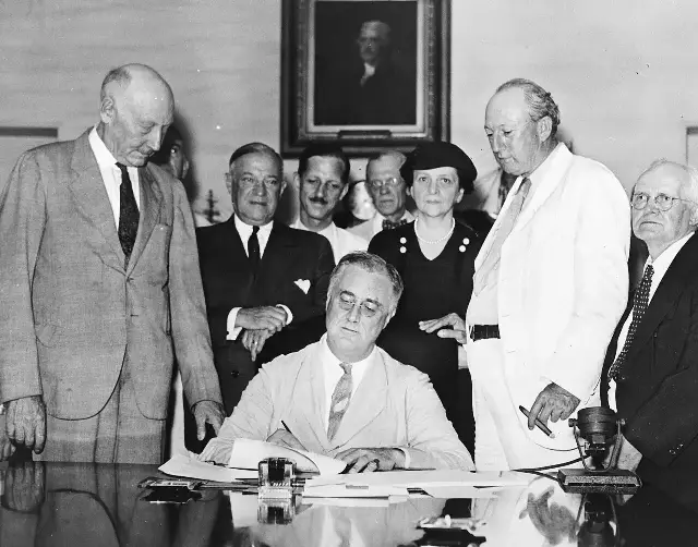 President Franklin D. Roosevelt signs the Social Security Act on August 14, 1935, surrounded by officials