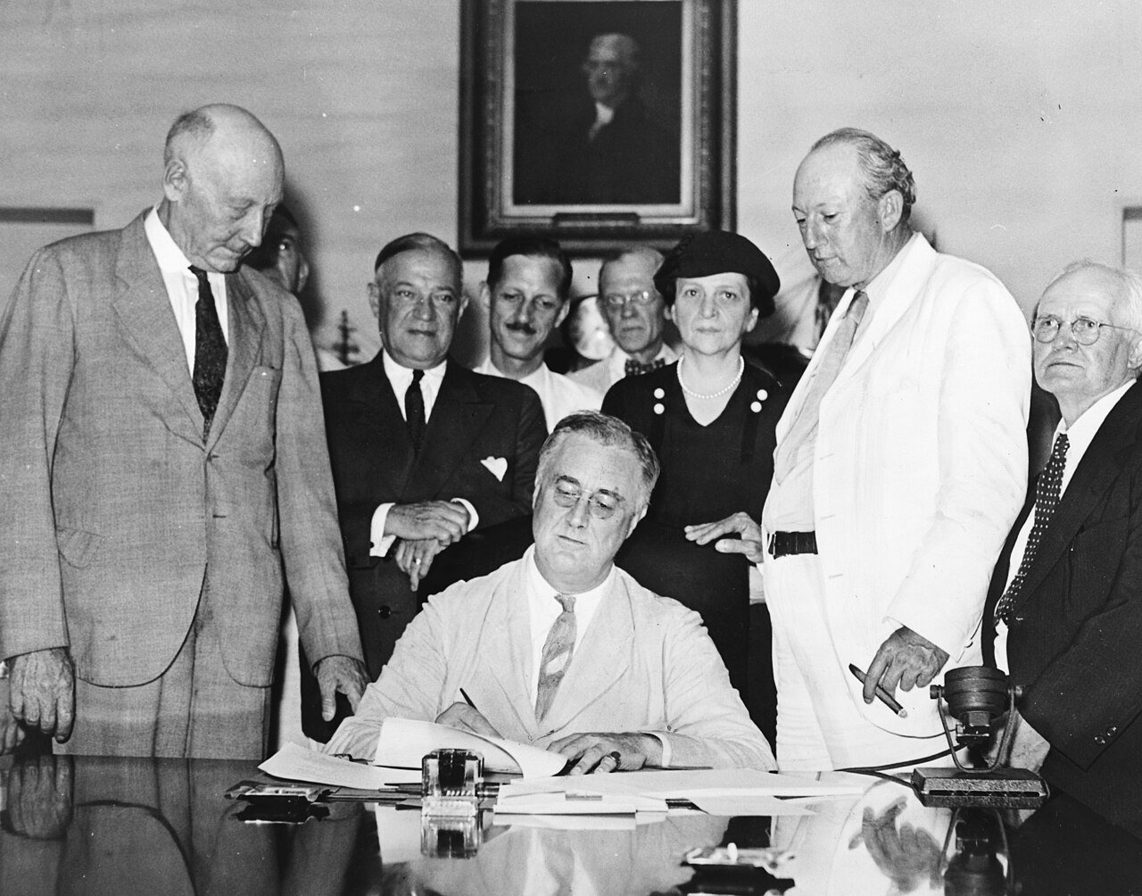 President Franklin D. Roosevelt signs the Social Security Act on August 14, 1935, surrounded by officials
