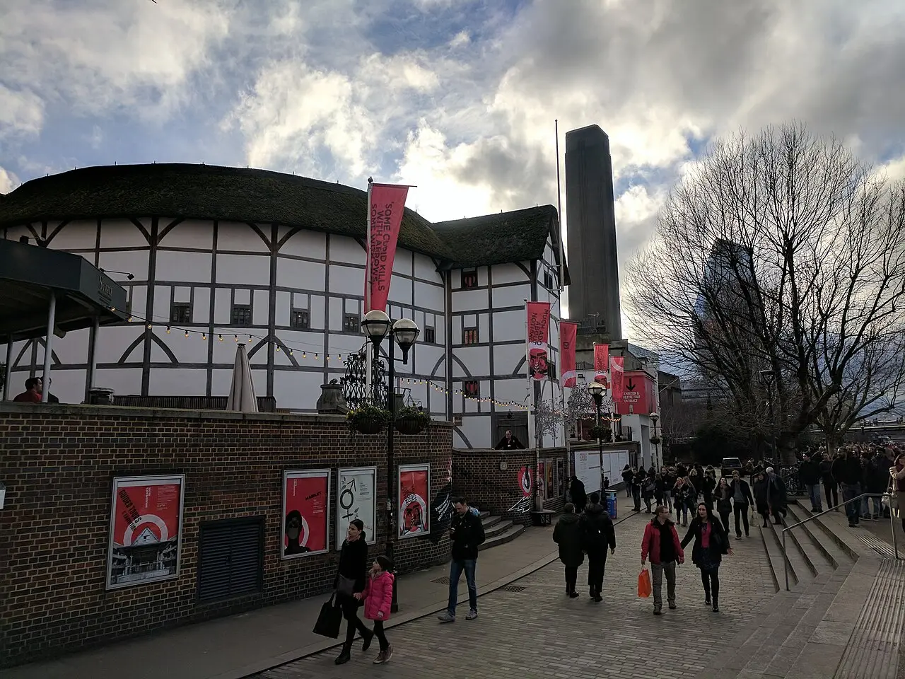 The reconstructed Shakespeare's Globe Theatre in London, a white timber-framed playhouse with a thatched roof, seen from the riverside walkway.