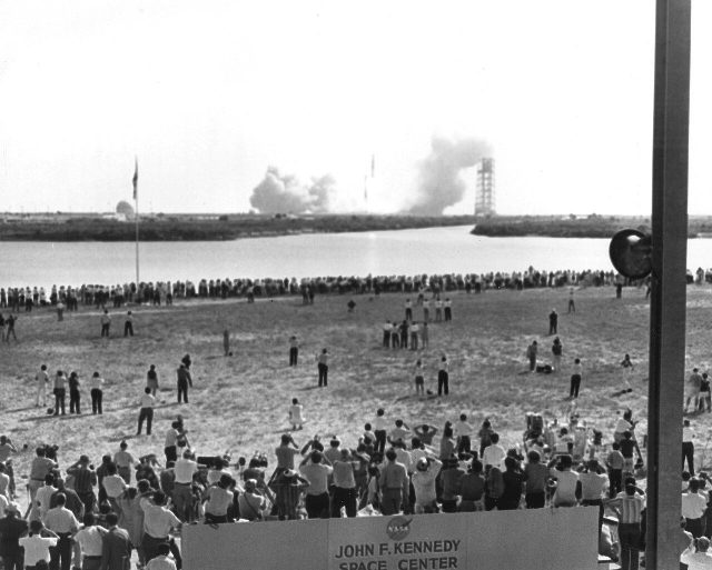 Thousands of reporters and spectators at the Kennedy Space Center press site watch the Apollo 11 Saturn V lift off on July 16, 1969.