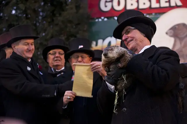 Punxsutawney Phil the groundhog held aloft by a top-hatted member of the Groundhog Club at Gobbler's Knob on Groundhog Day.