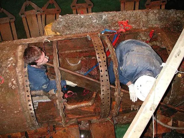 Conservators working inside the rusted hull of the H.L. Hunley after its recovery from Charleston harbor