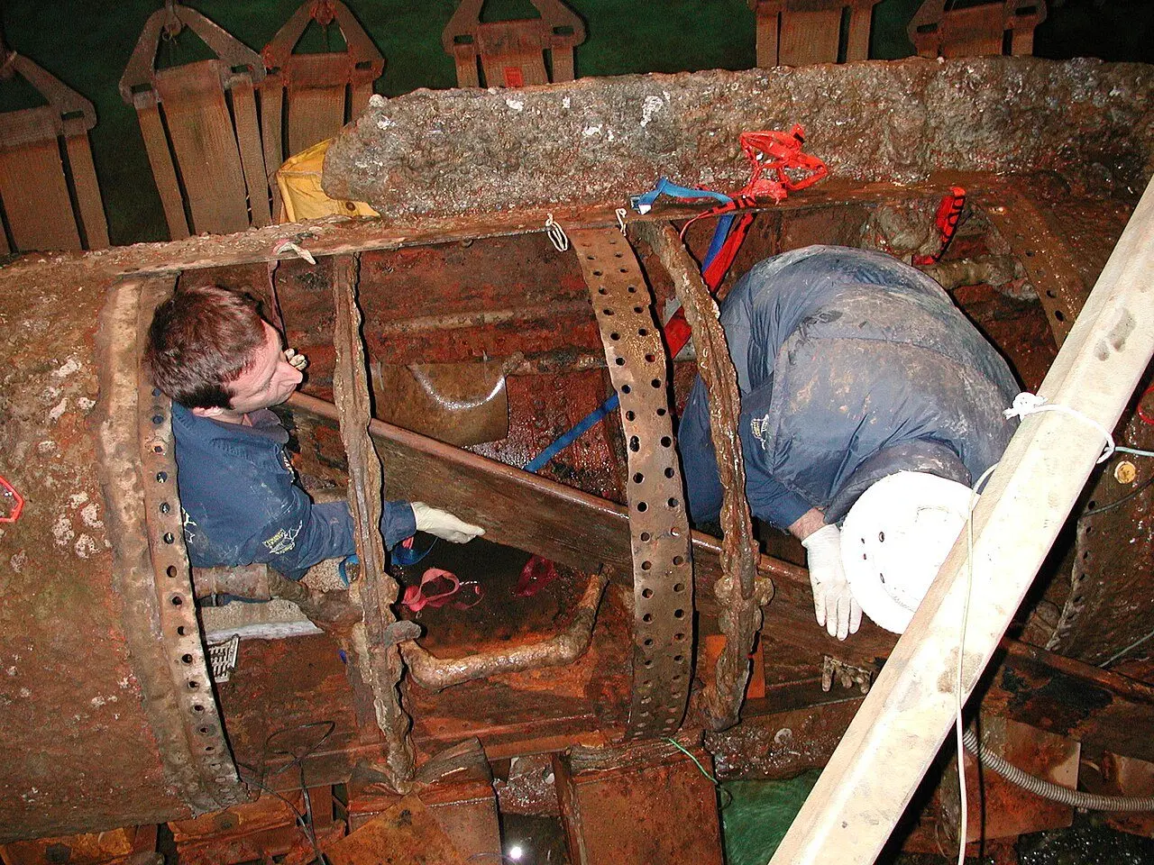 Conservators working inside the rusted hull of the H.L. Hunley after its recovery from Charleston harbor