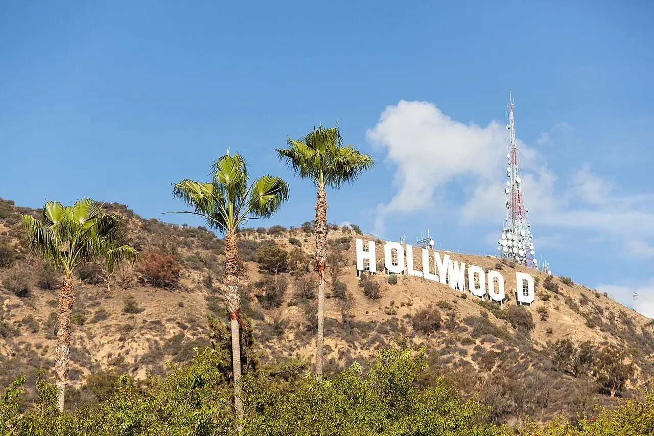 The Hollywood sign on Mount Lee above Los Angeles, with palm trees in the foreground.