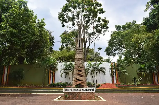 The Independence Monument in Kampala, Uganda — a sculpture of an adult lifting a newborn child on a plinth labeled 'Independence Monument', commemorating Uganda's independence on October 9, 1962.