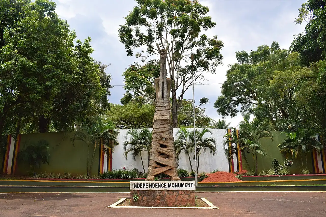 The Independence Monument in Kampala, Uganda — a sculpture of an adult lifting a newborn child on a plinth labeled 'Independence Monument', commemorating Uganda's independence on October 9, 1962.