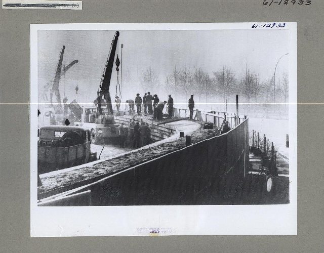 Archival photograph of East Germans constructing the Berlin Wall with cranes in 1961