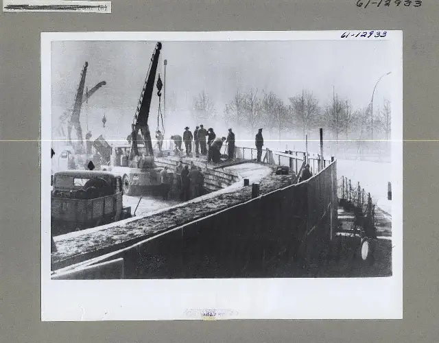 Archival photograph of East Germans constructing the Berlin Wall with cranes in 1961