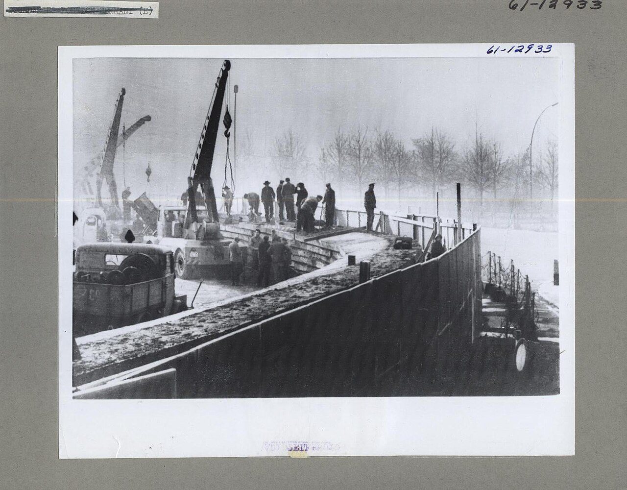 Archival photograph of East Germans constructing the Berlin Wall with cranes in 1961
