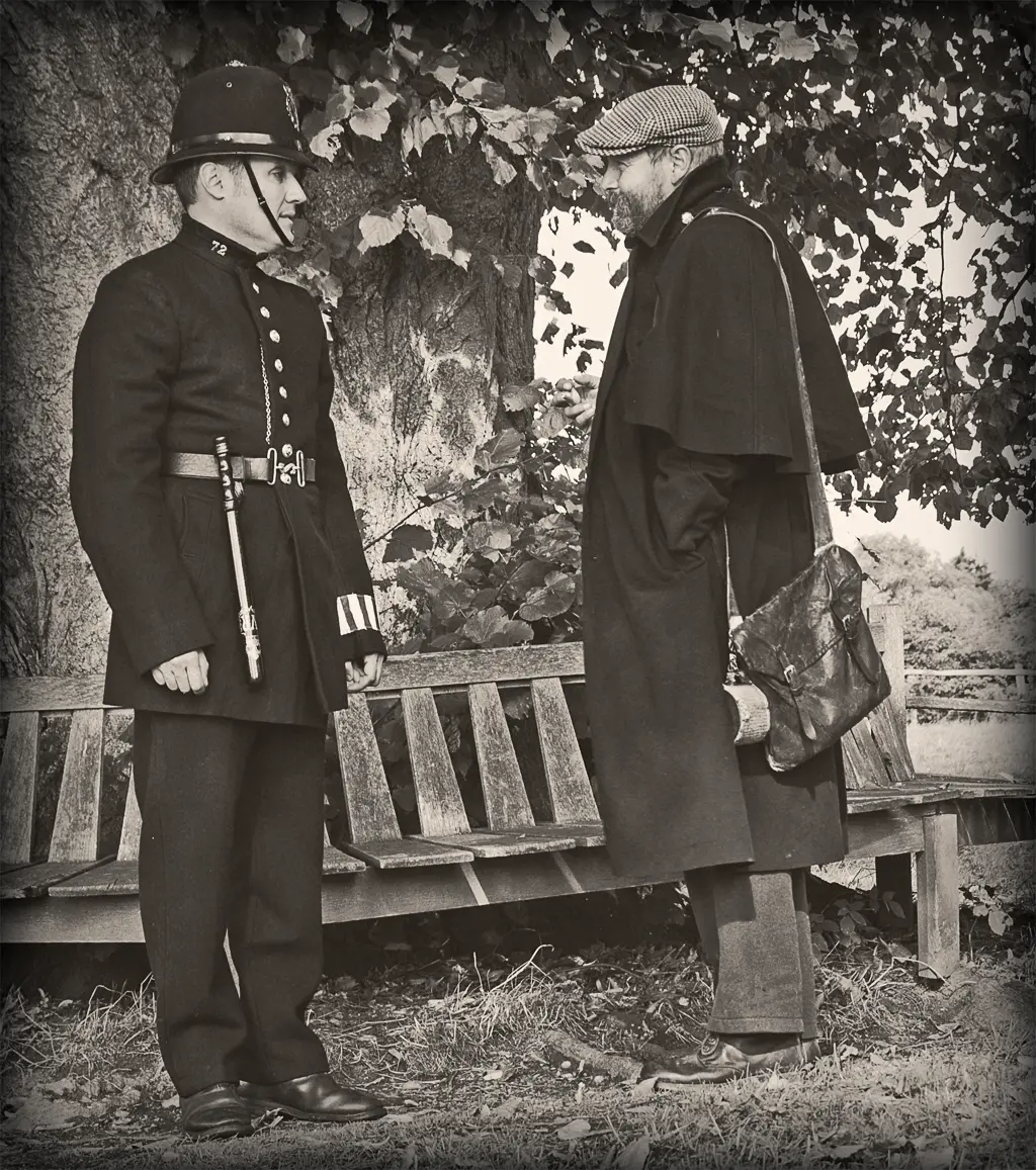 A reenactor dressed as a Victorian-era London police constable in a top hat and long blue coat, speaking with a costumed civilian