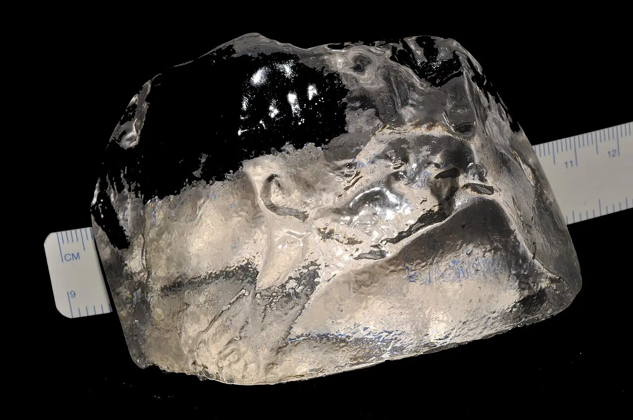 A full-size resin reproduction of the rough Cullinan diamond beside a ruler, showing its fist-sized scale (reproduction, not the original stone).