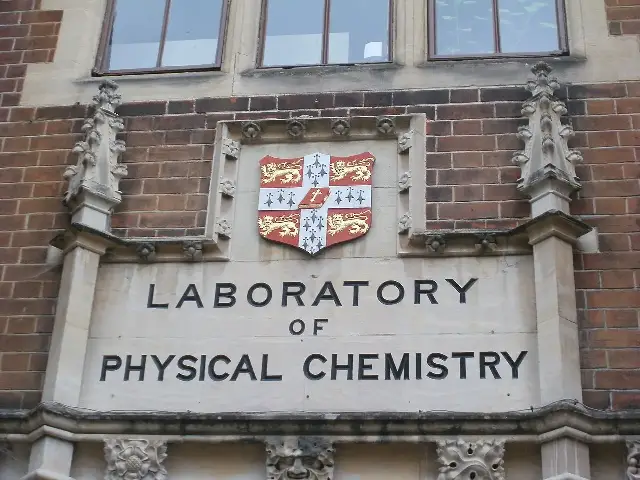 The carved stone entrance of a University of Cambridge laboratory building, with the university crest above the words 'Laboratory of Physical Chemistry' — the Cambridge research world where Watson and Crick unraveled DNA's structure.