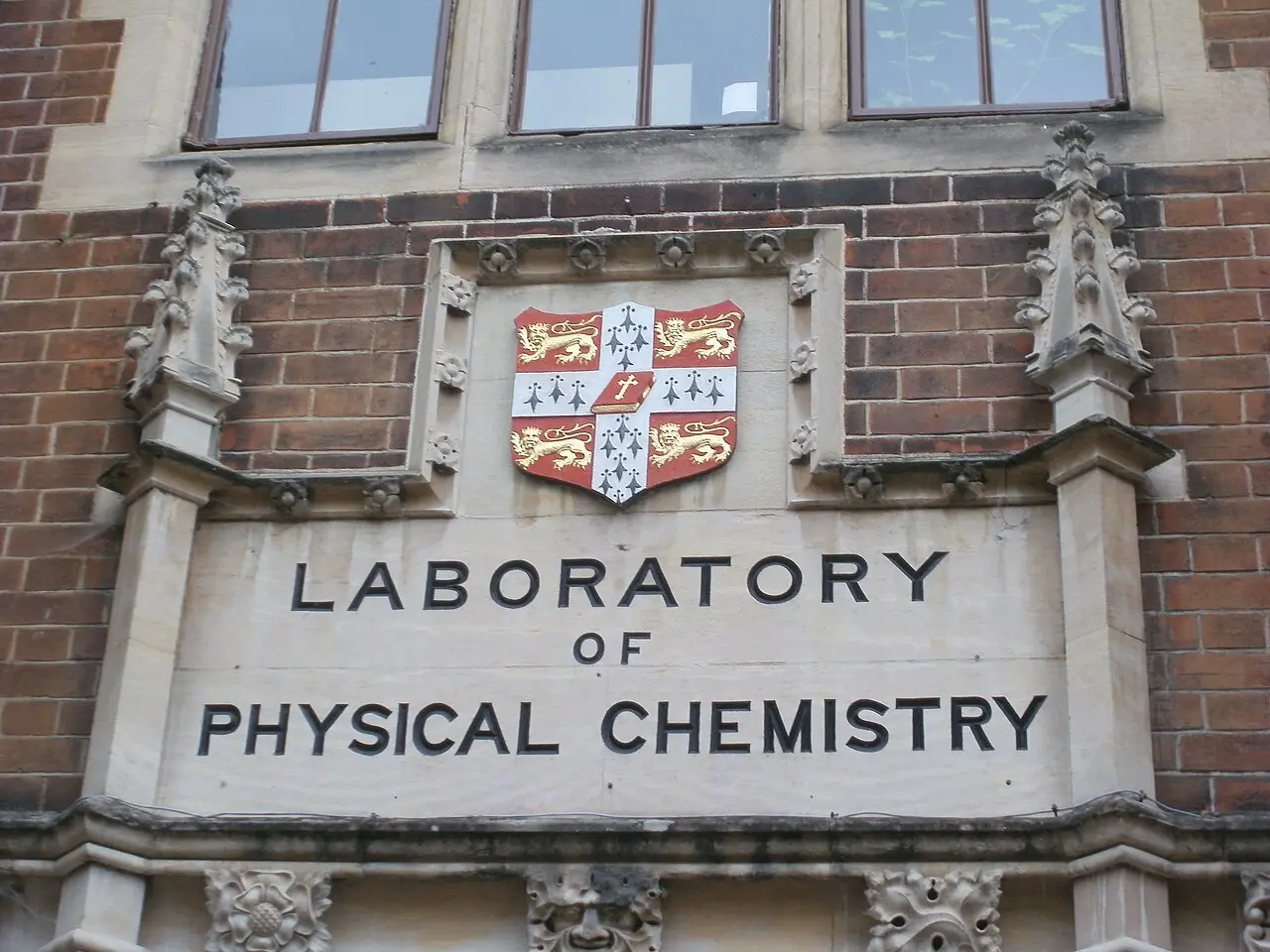 The carved stone entrance of a University of Cambridge laboratory building, with the university crest above the words 'Laboratory of Physical Chemistry' — the Cambridge research world where Watson and Crick unraveled DNA's structure.