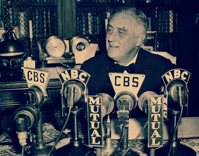 President Franklin D. Roosevelt broadcasting a radio address from his home in Hyde Park, New York, on November 4, 1938, surrounded by CBS, NBC, and Mutual network microphones.