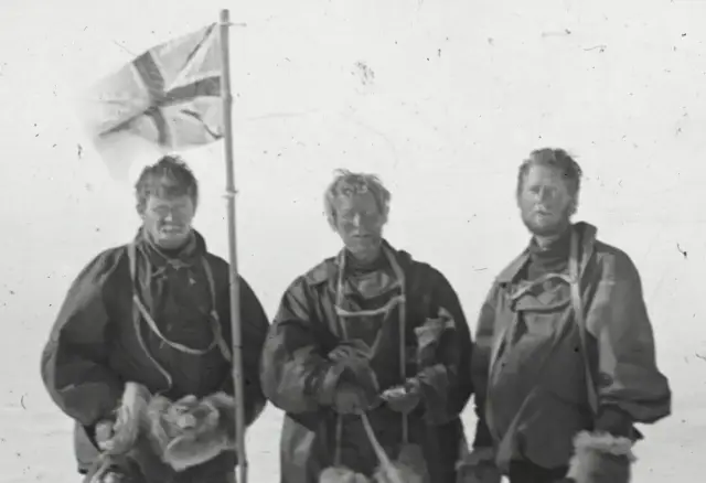 Three exhausted members of Shackleton's Nimrod expedition — Alistair Mackay, Edgeworth David and Douglas Mawson — with the Union Jack at the South Magnetic Pole, January 1909.