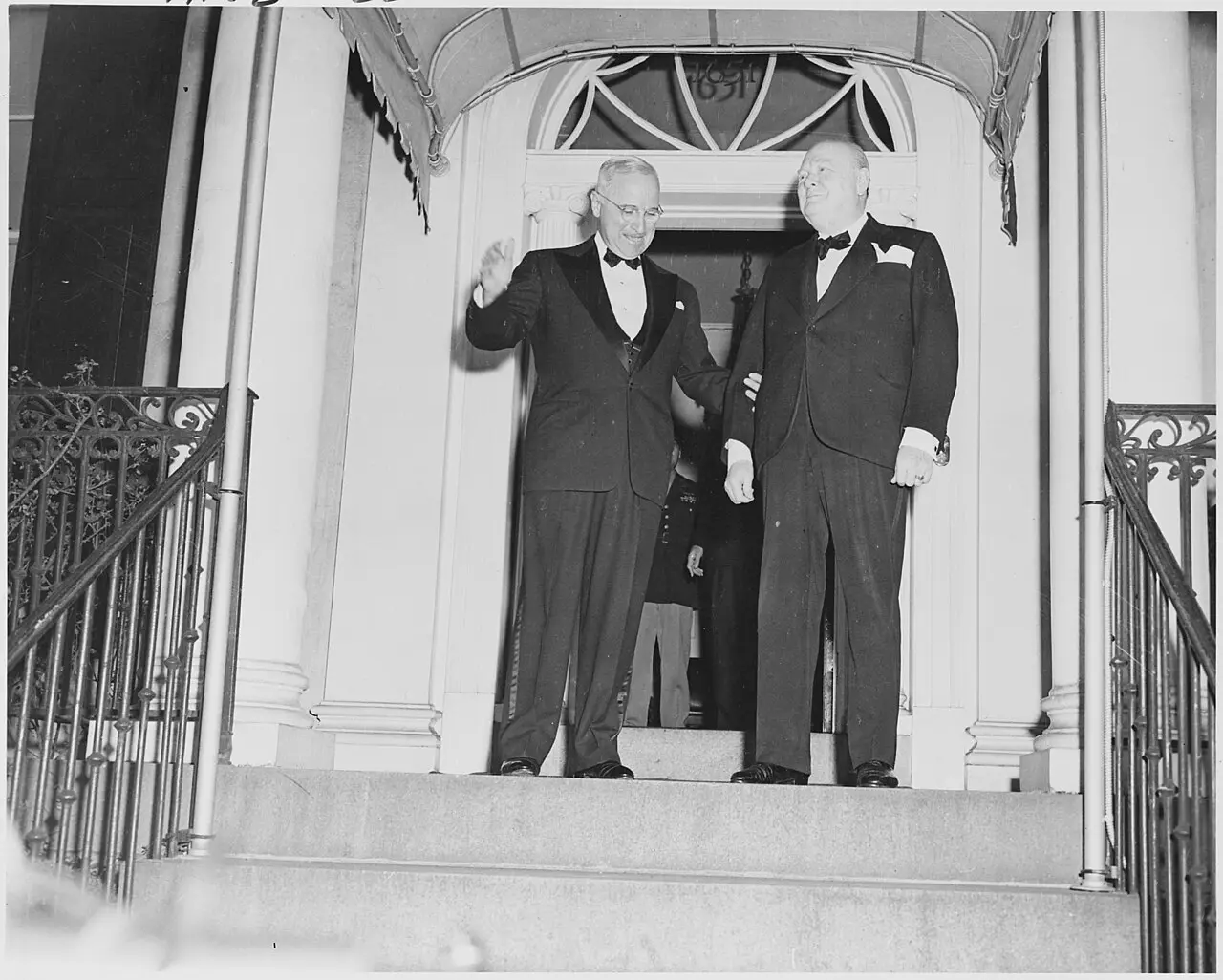 A 1946 photograph of Winston Churchill and President Harry Truman in evening dress, smiling together outside Blair House in Washington, D.C.