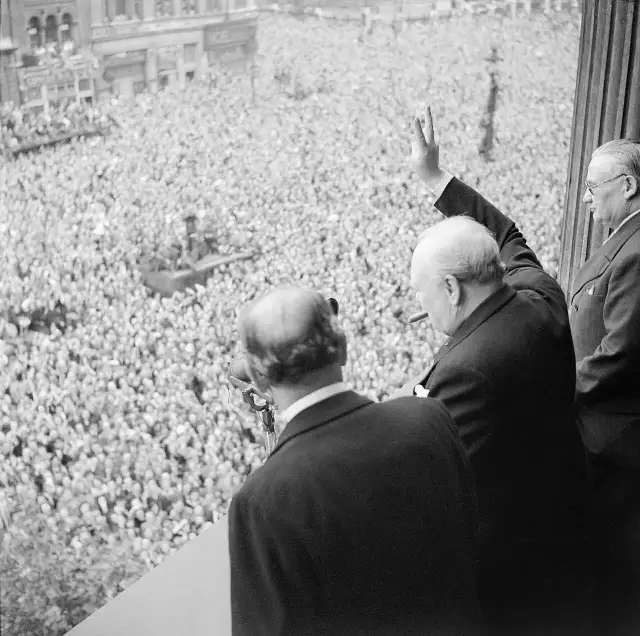Churchill gives his V-sign to cheering crowds in Whitehall on VE Day, 8 May 1945 — an earlier photograph; illustrative.