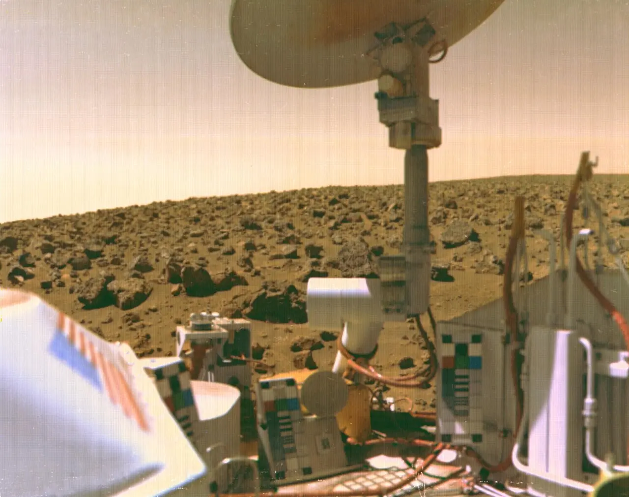 A view across the Viking 2 lander's deck to the rocky surface of Utopia Planitia, Mars, with the lander's antenna against the Martian sky.