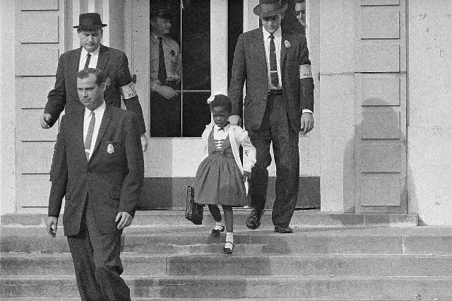 Six-year-old Ruby Bridges walking down the steps of William Frantz Elementary School escorted by U.S. Marshals on November 14, 1960.