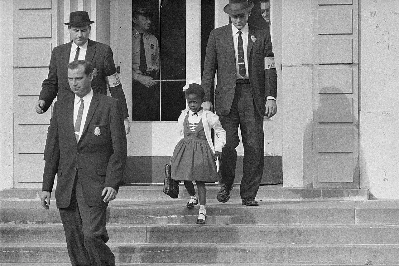 Six-year-old Ruby Bridges walking down the steps of William Frantz Elementary School escorted by U.S. Marshals on November 14, 1960.