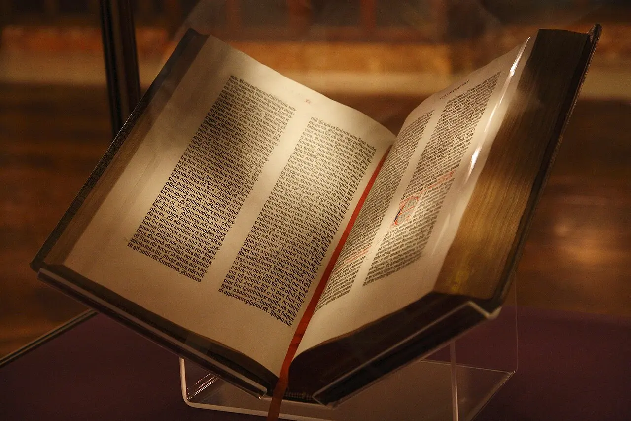 A Gutenberg Bible open on display at the New York Public Library, its pages of dense black-letter type visible.