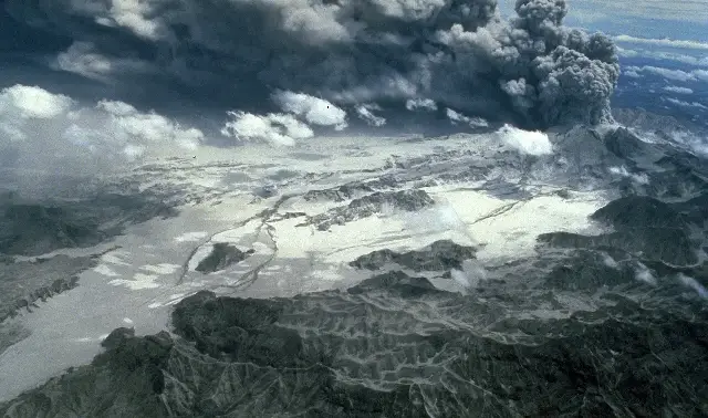 Aerial view of an eruption column rising from Mount Pinatubo over the ash-buried Marella River Valley during the volcano's June 1991 eruption sequence.