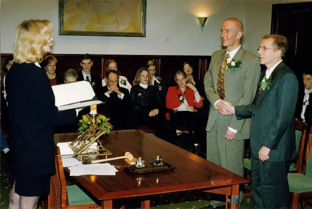 Two men holding hands before a wedding officiant at a civil marriage ceremony in the Netherlands; illustrative.