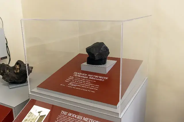 The Hodges meteorite on display in a case at the Alabama Museum of Natural History, with its exhibit label describing the November 30, 1954 strike (modern photograph).