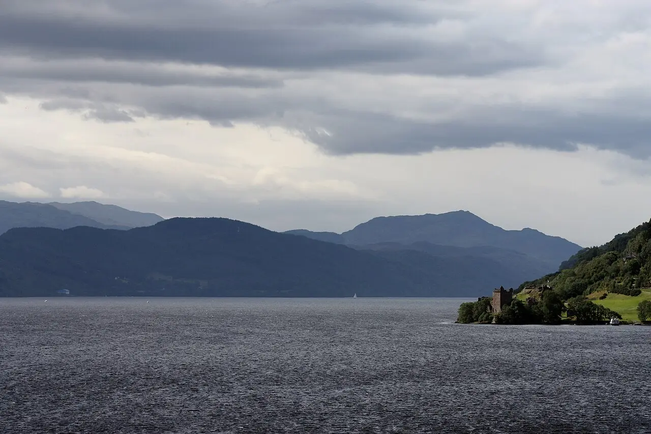 Loch Ness with the ruins of Urquhart Castle on its shore under a moody sky