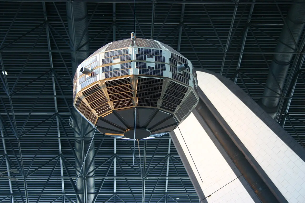 The Alouette 1 satellite on display, showing its cylindrical body covered in solar cells with long antennas extended