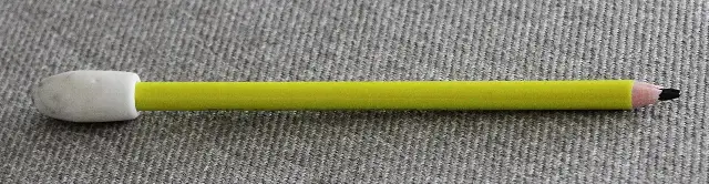 A yellow pencil with a white eraser fitted at its end, lying on a textured gray surface