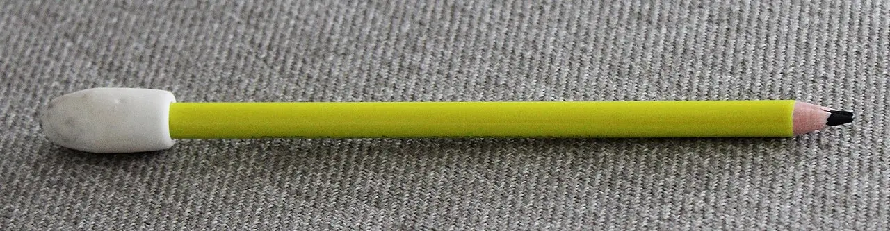 A yellow pencil with a white eraser fitted at its end, lying on a textured gray surface