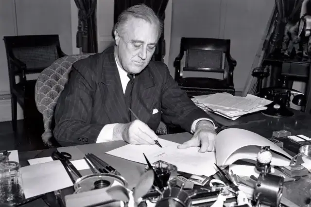 President Franklin D. Roosevelt seated at his desk signing the Lend-Lease bill, March 11, 1941