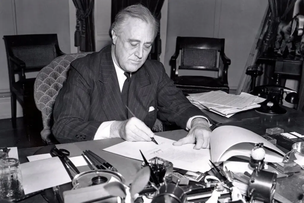 President Franklin D. Roosevelt seated at his desk signing the Lend-Lease bill, March 11, 1941