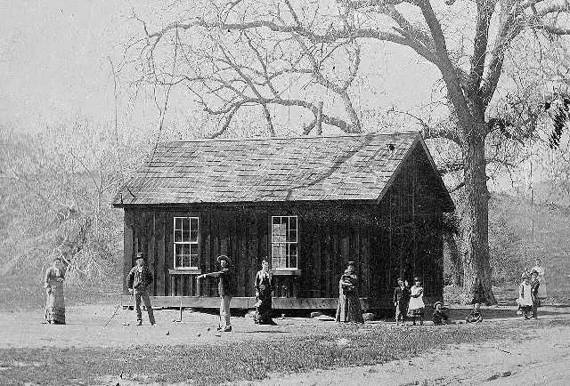 An 1881 tintype photograph showing Billy the Kid playing croquet with others outside a wooden building in New Mexico.