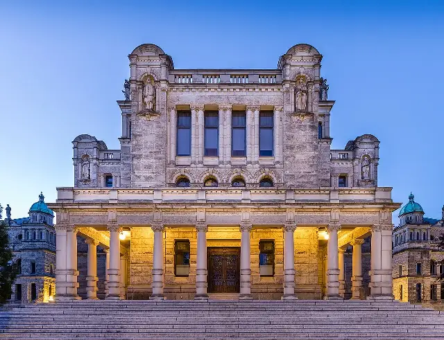 The British Columbia Parliament Buildings in Victoria, photographed at dusk with the stone facade illuminated