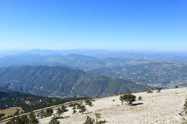 The sweeping view from the limestone summit of Mont Ventoux over the mountains and valleys of Provence, France, under a clear blue sky.